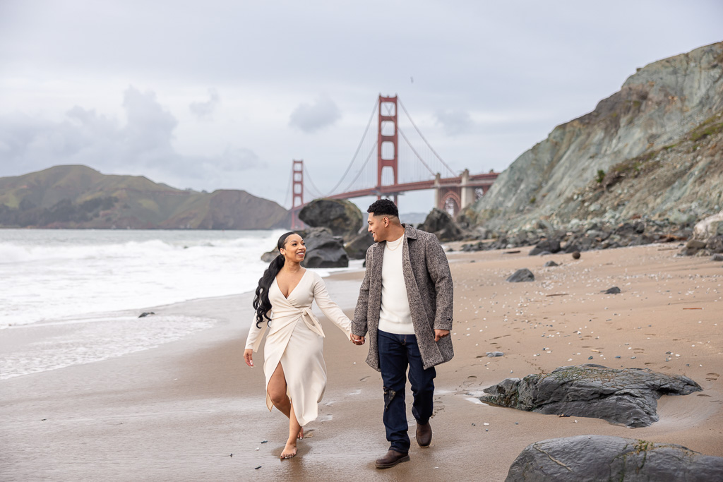 beautiful couple taking engagement photos at the Golden Gate Bridge beach