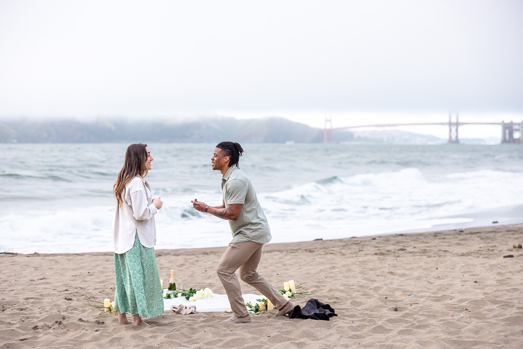 kneeling down for surprise proposal at a picnic blanket