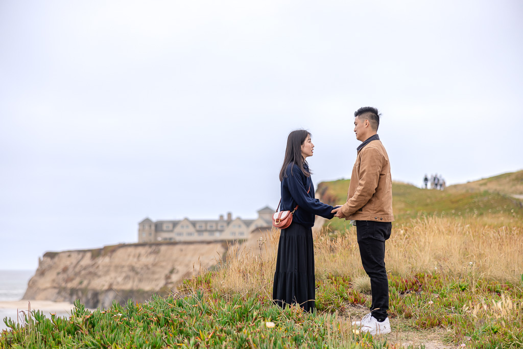 couple standing atop a cliff holding hands and facing each other
