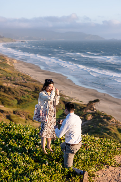 surprise proposal on a cliff overlooking the ocean at sunset