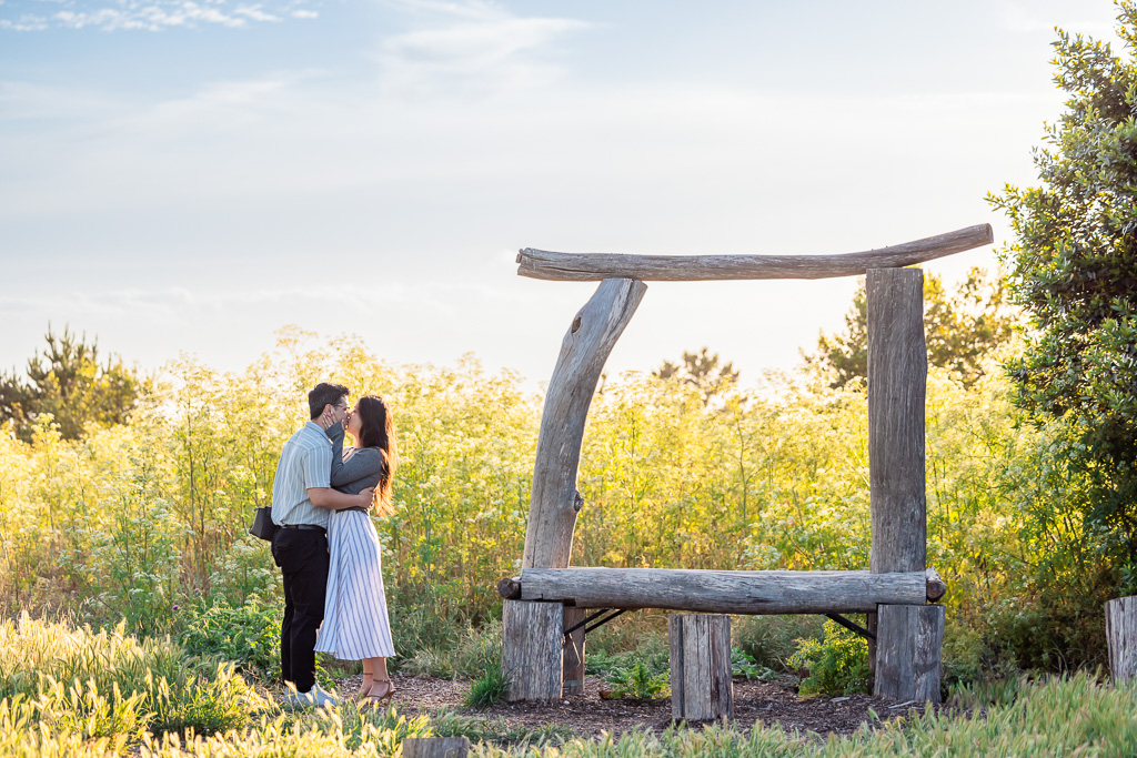 engagement photos near a wooden arbor at sunset