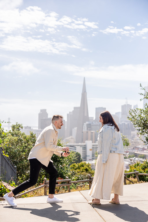 kneeling down to propose marriage in front of the San Francisco skyline