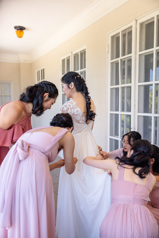 bride and bridesmaids helping with dress