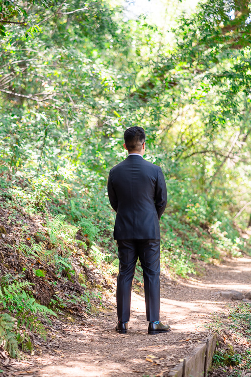 groom waiting for first look at hiking trail