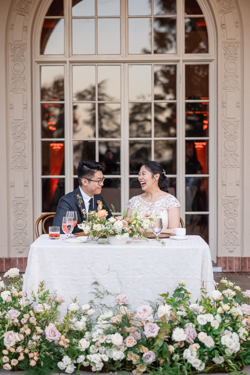 bride and groom at sweetheart table laughing