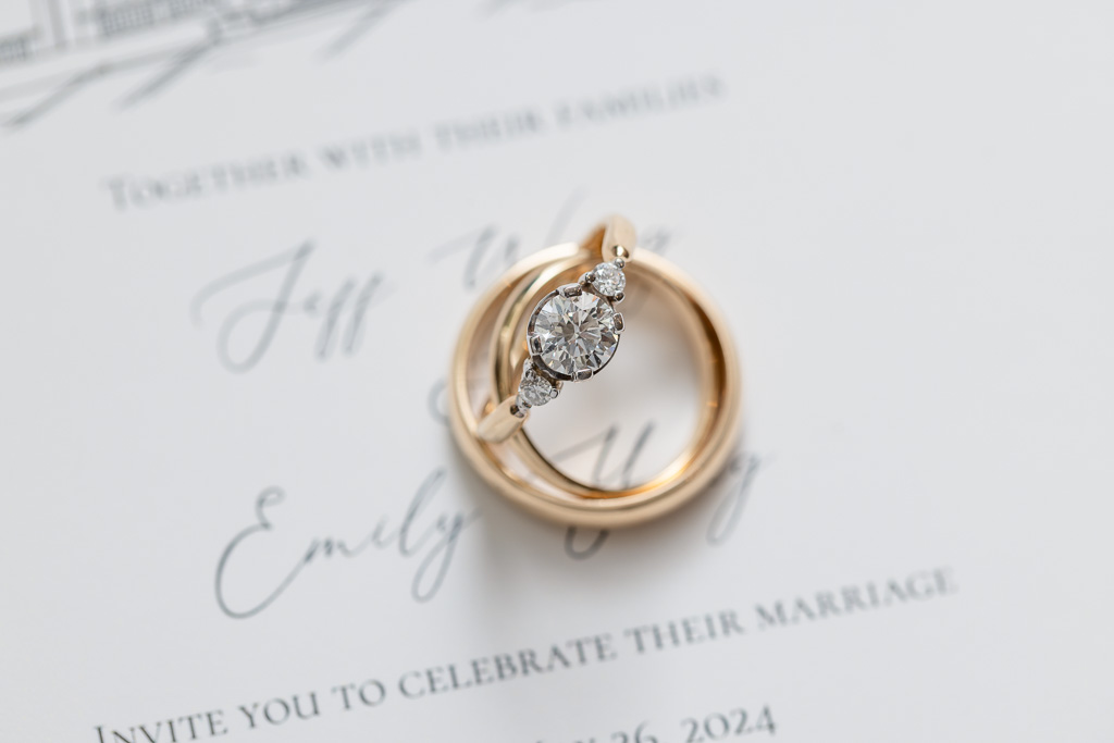 macro photo of wedding and engagement rings on invitation