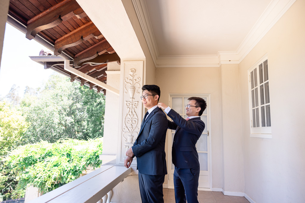 best man helping groom with jacket and collar