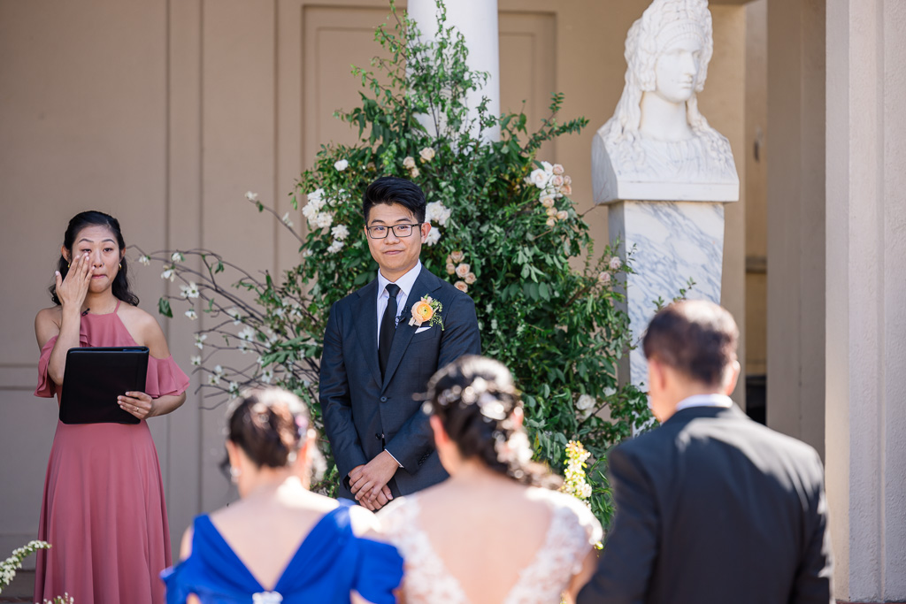 groom watching as bride and parents walk down the aisle