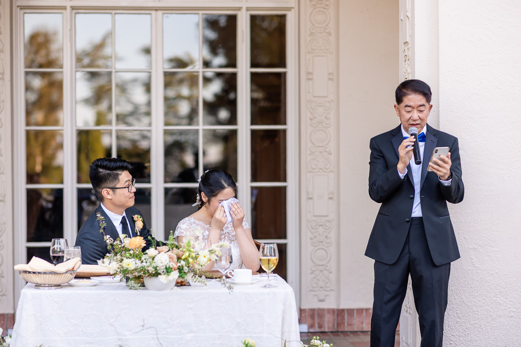 bride wiping a tear during her dad's speech