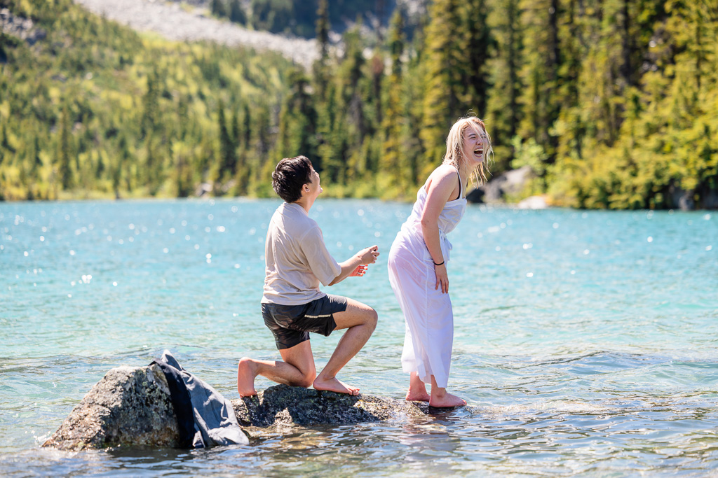 surprise proposal of a couple in a glacial lake on a rock