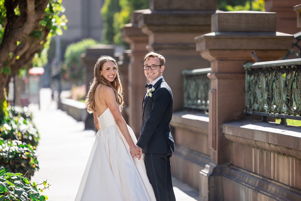 bride and groom walking along the sidewalk and looking back