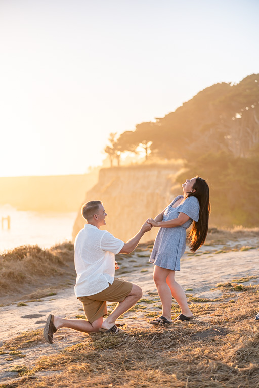 sneaky proposal photo at Davenport Beach cliffside at sunset