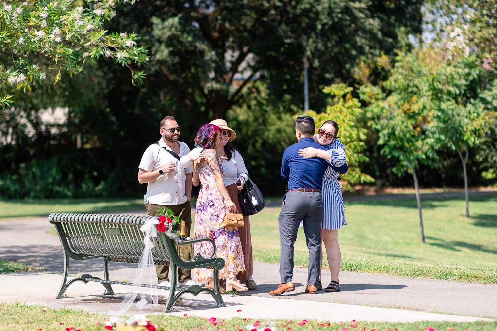 friends hugging and congratulating couple after engagement