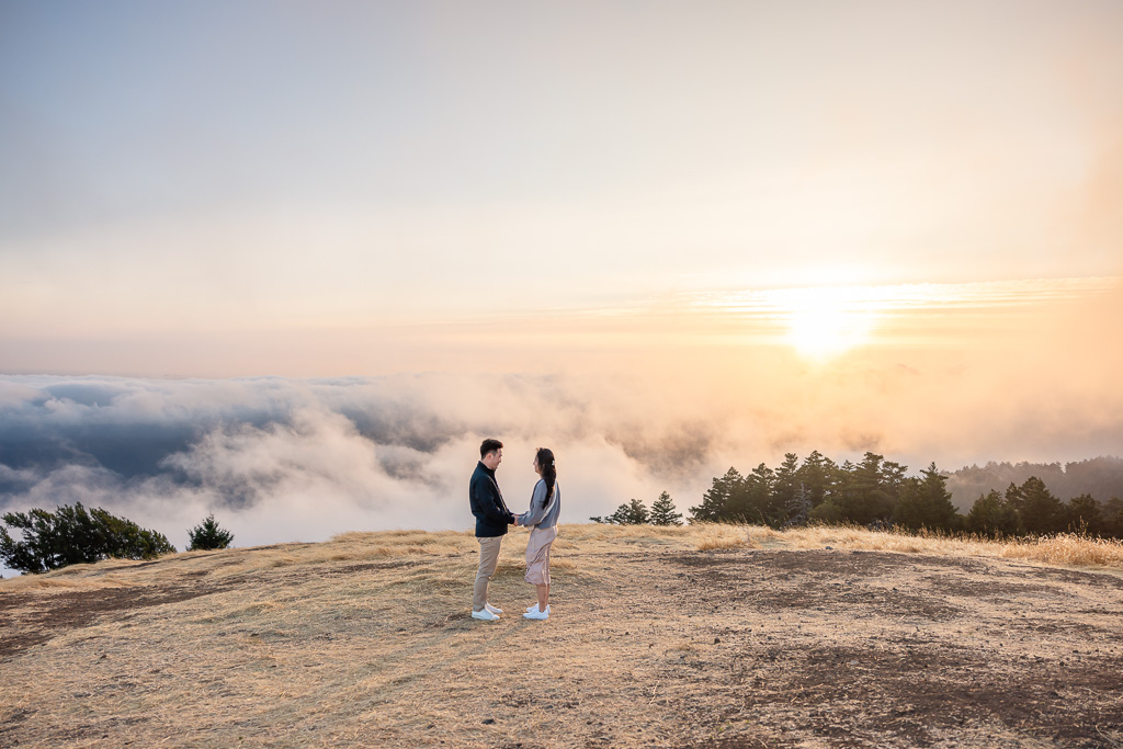 couple standing on the edge of the world in front a sea of clouds