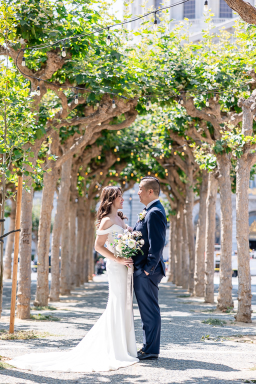 beautiful moment between bride and groom in a row of trees