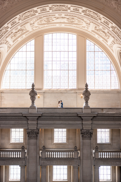 zoomed-out photo of bride and groom in a romantic pose at City Hall