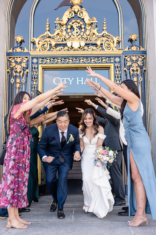 guests forming a tunnel for the bride and groom to run through out the main City Hall door