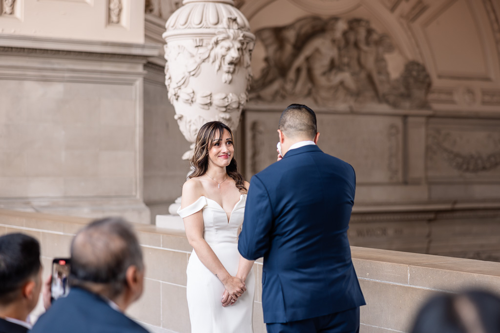 bride looking at groom while he wipes a tear