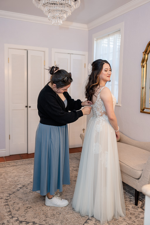 bridesmaid helping button up bride's dress