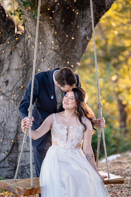 bride and groom on a swing set on a tree