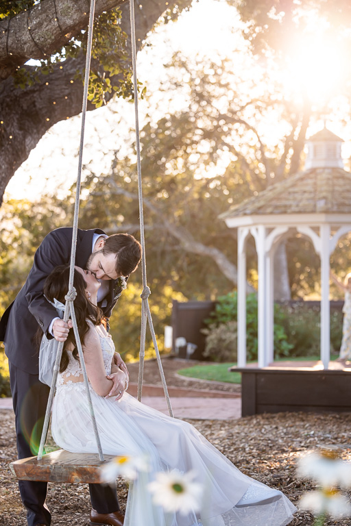 romantic photo of bride and groom on swing set with sun flare