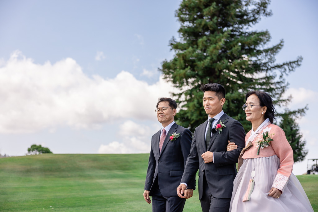 groom entering wedding ceremony with both parents