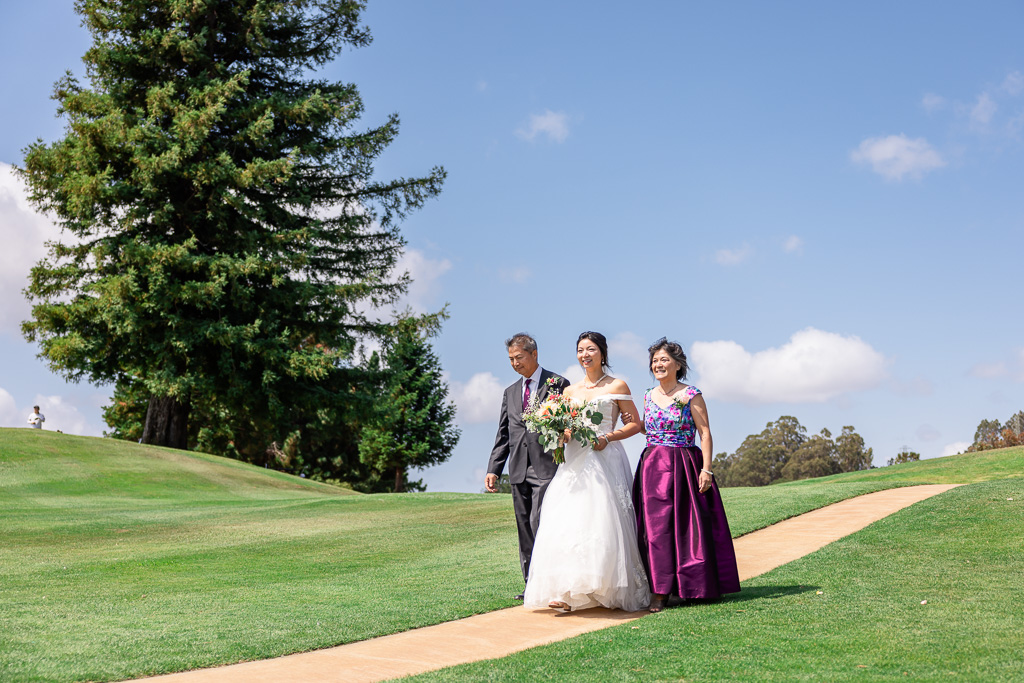 bride walking down the aisle with both parents