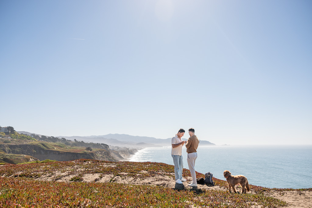 putting on the engagement ring while standing on top of a cliff overlooking the ocean