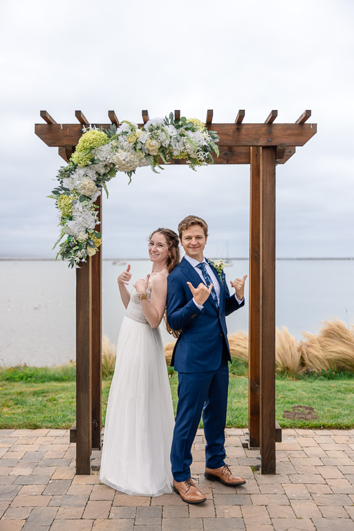 fun pose near the wedding arbor