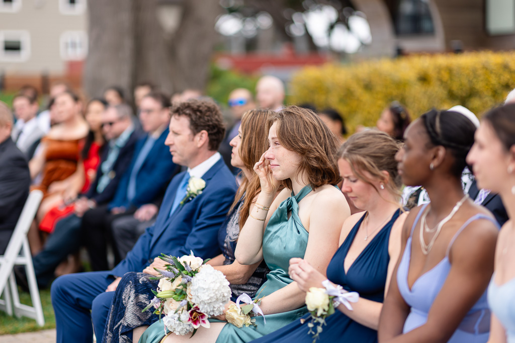 bridesmaid wiping away a tear during ceremony