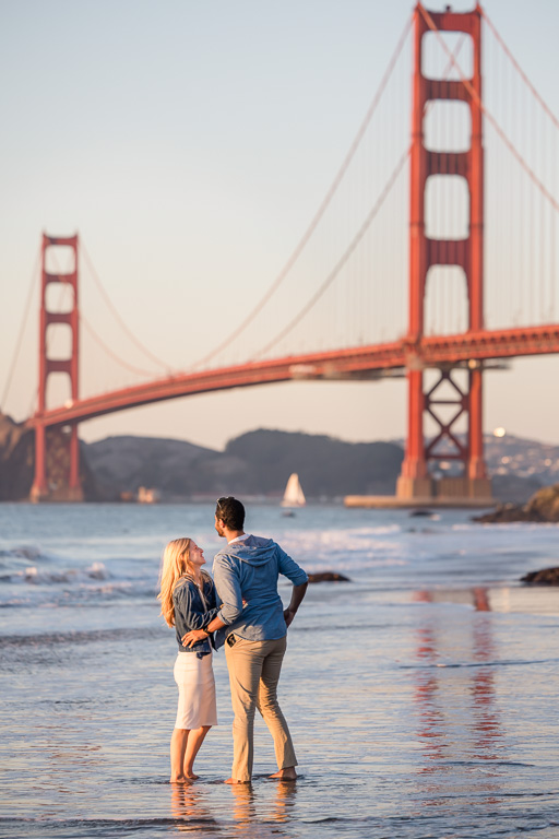 couple standing together in the low tide below the Golden Gate Bridge