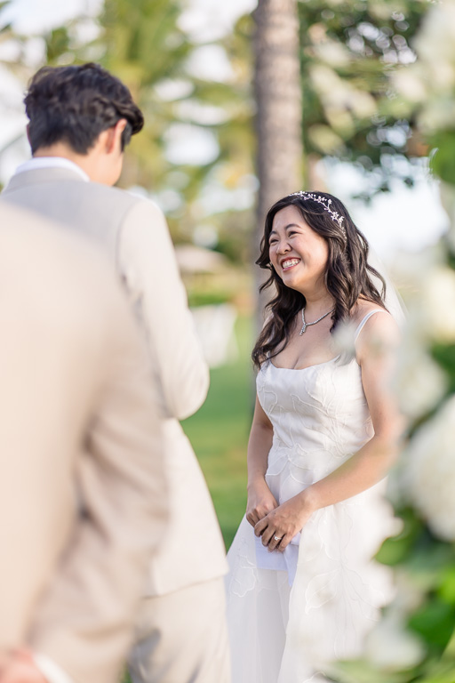 bride smiling while the groom gives his vows