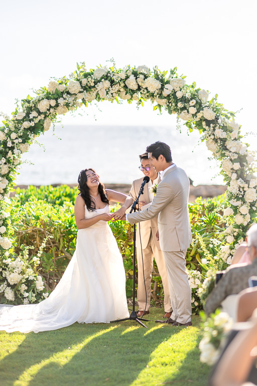 bride laughing while she tries to put the ring on her groom