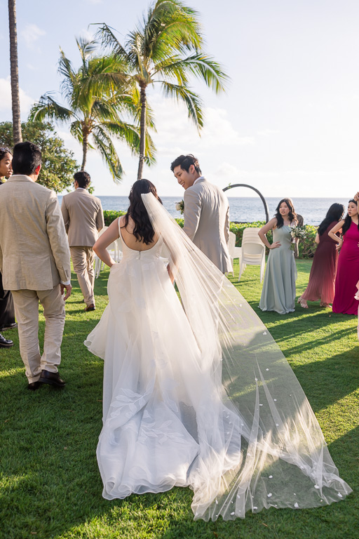 candid photo of bride and groom showing off her long veil