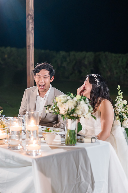 bride and groom laughing and facepalming at a speech