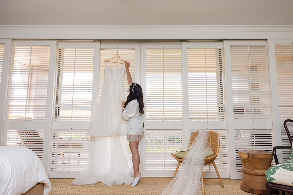 bride reaching for her wedding dress in hotel room