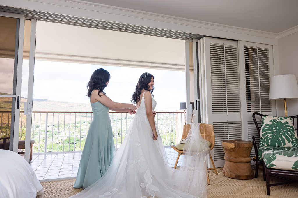 bridesmaid helping bride with her wedding dress