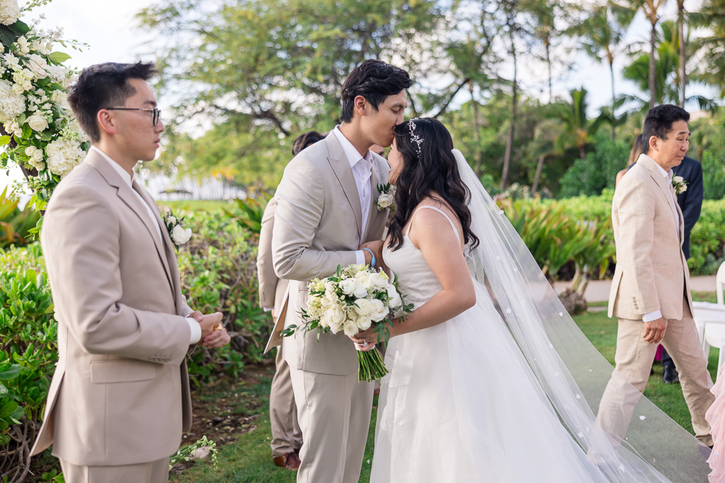 groom giving the bride a kiss on the forehead as she approaches the end of the aisle