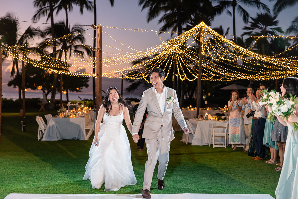 newlywed couple happily running onto the dance floor for a nighttime outdoor first dance