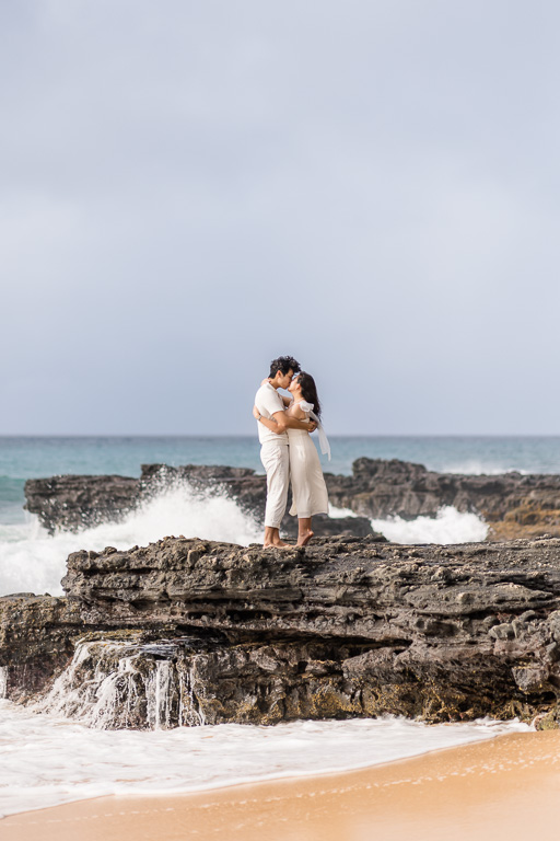 engagement photos on the rocks at Sandy Beach with waves splashing around