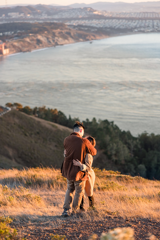 a couple hugging on a grassy hillside