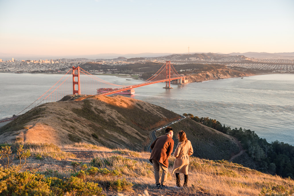 couple enjoying the view of the Golden Gate Bridge at sunset from a high vantage point