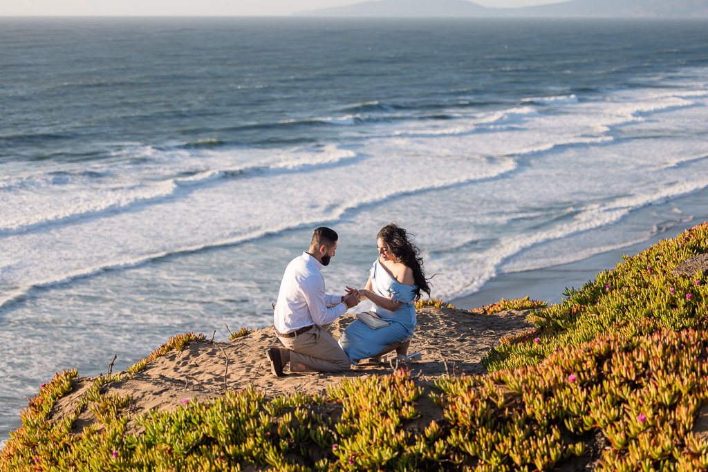 hidden photographer for surprise proposal on a cliff edge by the ocean