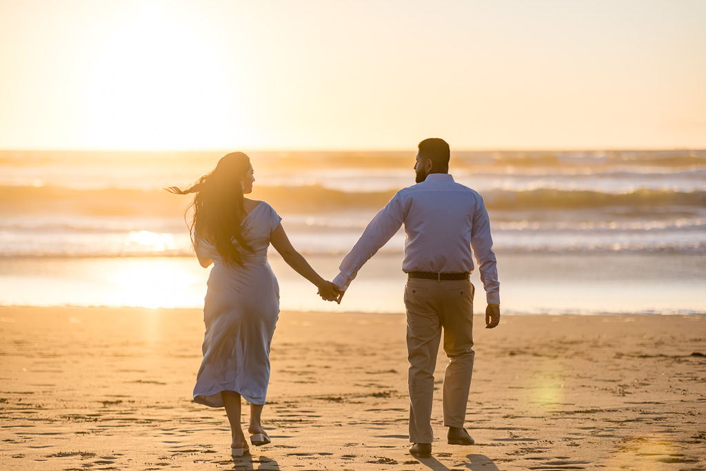 artistic dreamy photo of couple walking into the sunset at the beach