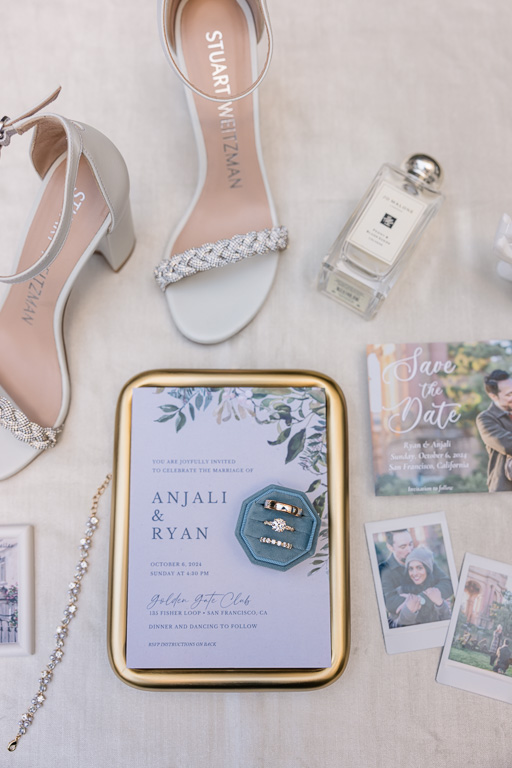 wedding details flat lay with invitation, rings, save-the-date, shoes, perfume