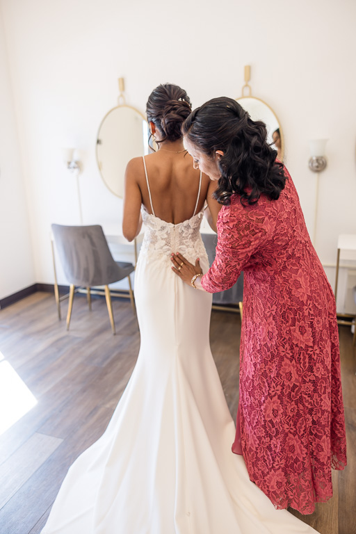 mother of the bride helping bride with the dress