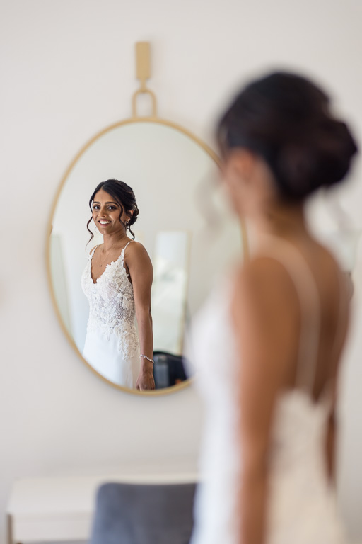 bride checking herself out in the mirror after putting on her dress