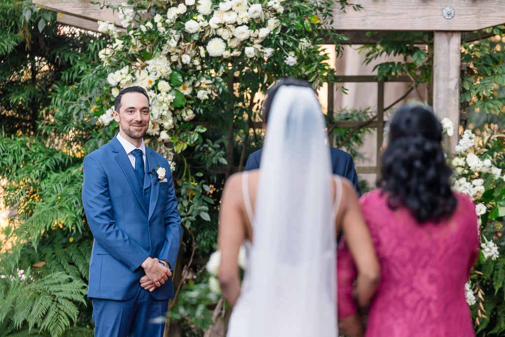 groom watching as bride is walking down the aisle to him