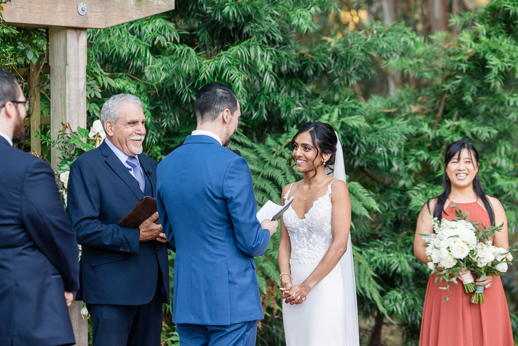 bride smiling at the groom as he delivers his wedding vows