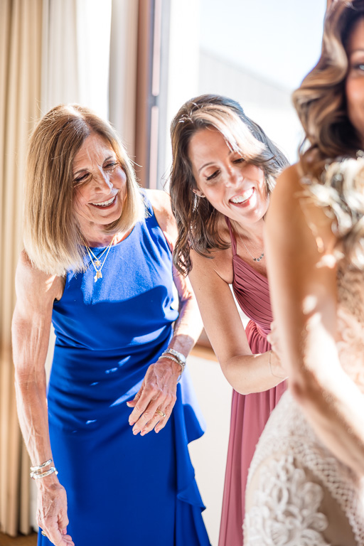 bridesmaids helping to button bride's dress